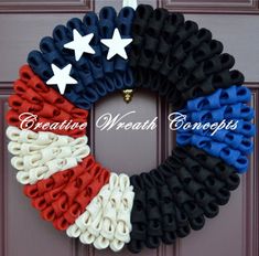 an american flag wreath hanging on the front door with white stars and red, white, and blue ribbon