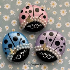 three ladybug buttons with pearls on them sitting on top of a table covered in daisies