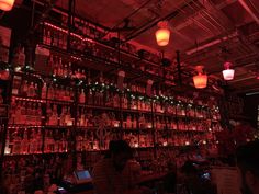 the bar is filled with many different types of liquor bottles and lights on the wall