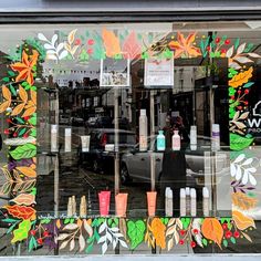 a store front window with many different items in the glass and flowers on the windows