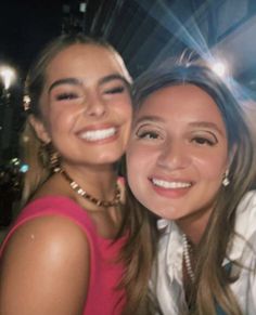 two young women are smiling for the camera while posing for a photo in front of some lights
