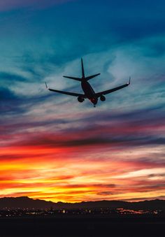 an airplane is flying in the sky at sunset