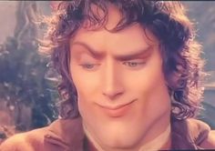 a close up of a person wearing a suit and tie with long curly hair, looking at the camera