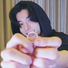 a woman in a hoodie is holding out her finger to the camera while wearing a ring