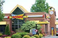 a sonic restaurant with yellow awnings on the front and red table chairs outside