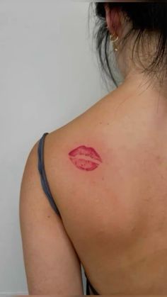 a woman's back with a red lip tattoo on her upper arm and shoulder