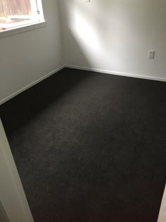 an empty room with black carpet and white walls