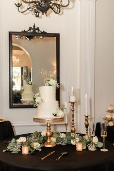a table topped with a white cake next to candles and flowers on top of it