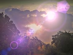 the sun shines brightly in front of some trees and clouds on a cloudy day