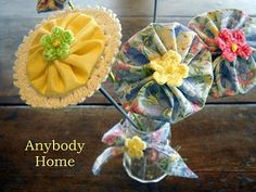 three fabric flowers are in a vase on a wooden table with the words, any body home