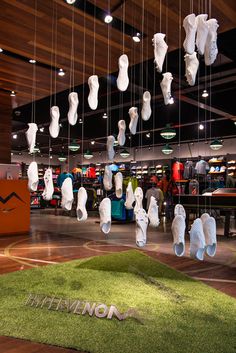 there are many pairs of shoes hanging from the ceiling in this store, which is decorated with artificial grass
