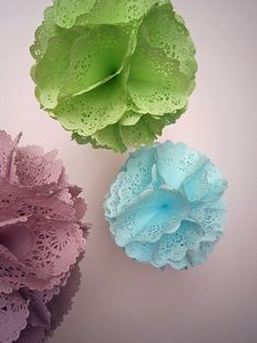 three different colored flowers on a white surface