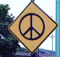 a yellow and black sign with a peace sign on it's side next to a blue pole