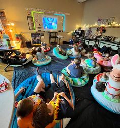 children are sitting on inflatables and watching television at the same time as they watch cartoons