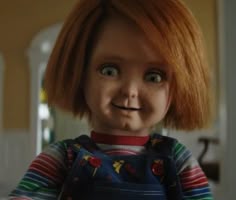 a creepy doll with red hair and blue overalls