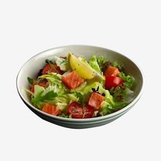 a salad in a bowl with tomatoes, lettuce and lemon wedges on top