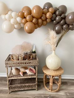some balloons are hanging on the wall near a table with a vase and other items