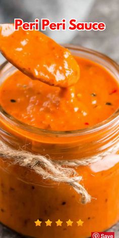 an orange sauce in a glass jar with a wooden spoon sticking out of the top