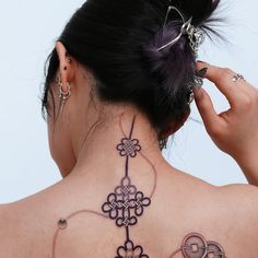 the back of a woman's neck with tattoos on her upper and lower part