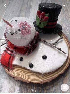 two snowmen sitting on top of a piece of wood