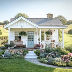 a small white house with flowers in the front yard