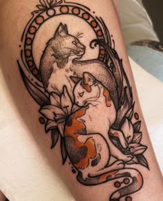 a tattoo with two cats sitting on top of each other and an orange fish in the middle