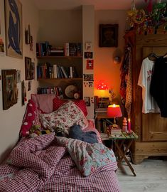 a bedroom with pink and white checkered sheets on the bed, bookshelf in the background