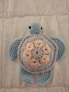 a crocheted turtle laying on top of a bed