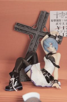a figurine sitting on the ground next to a cross