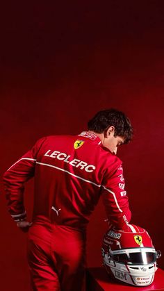 a man in a red suit and helmet leaning on a table with his hands behind his back