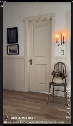 a chair sitting in front of a door next to a wall with pictures on it