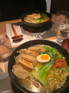 a bowl of ramen with an egg on top and other dishes in the background