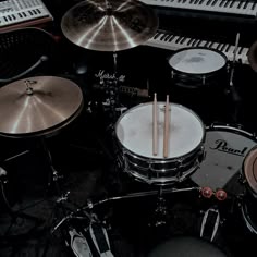 a drum set with two sticks in front of it and several keyboards on the side