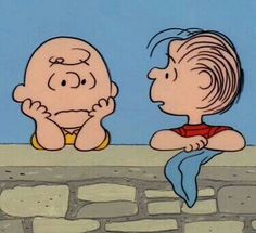 a charlie brown cartoon sitting on top of a stone wall next to a man with his head in his hands