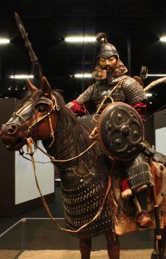 a statue of a man riding on the back of a brown horse in a museum