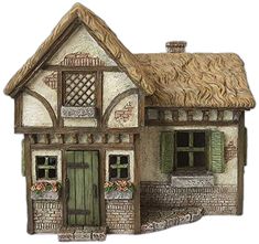 a small house with a thatched roof and green shutters on the front door