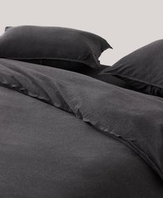 a bed with black sheets and pillows on it