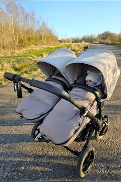 two baby strollers sitting side by side on the road