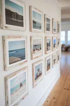 Whitewashed wooden frames hanging on a wall with seaside photographs.