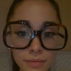 a woman with glasses on her face looking at the camera while she is taking a selfie