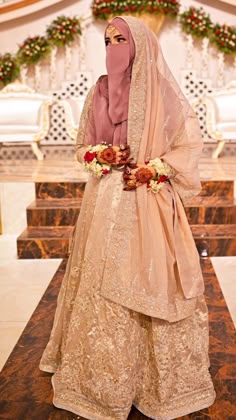 a woman wearing a veil and dress standing in front of a table with flowers on it