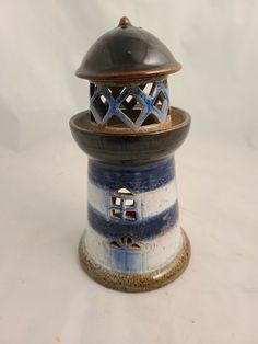 a small blue and white lighthouse with a metal dome on it's top sitting on a white surface