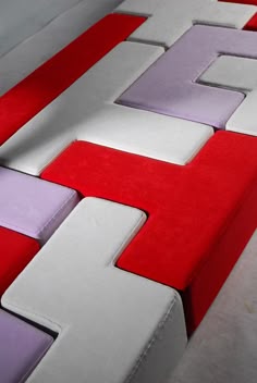 a red, white and purple couch sitting on top of a floor