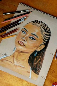 a pencil drawing of a woman's face on a piece of paper next to crayons