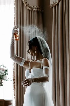 Bride in wedding dress and veil spraying wedding perfume