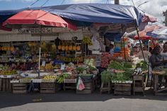 an open air market with people shopping for fruits and vegetables