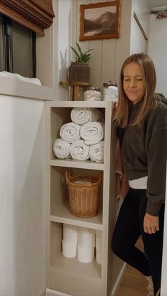 a woman standing next to a shelf filled with white towels