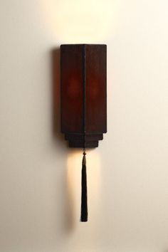 a wall mounted clock with a tassel hanging from it's side on a white wall