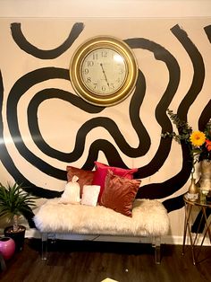 a living room with a clock on the wall next to a couch and some plants