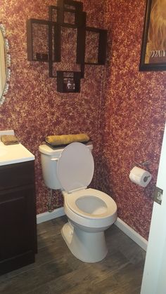 a white toilet sitting in a bathroom next to a sink and mirror on the wall